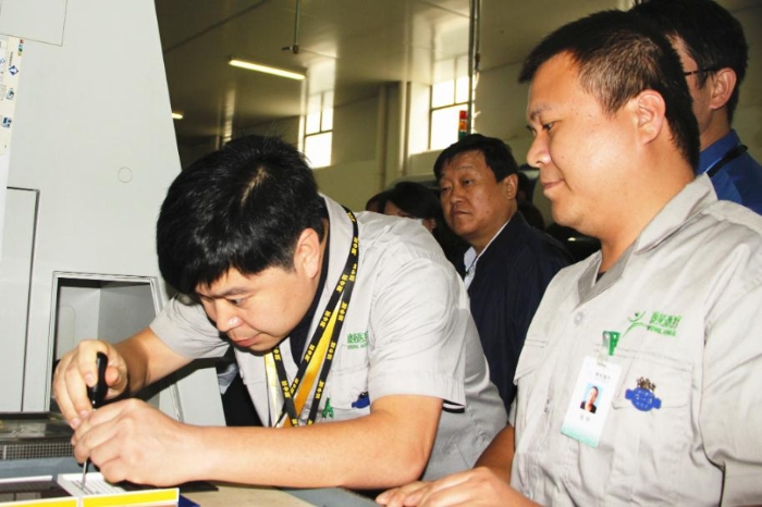 工作人员在生产车间现场向大家演示产品和工具的精准配合性能（贺一辰 摄）