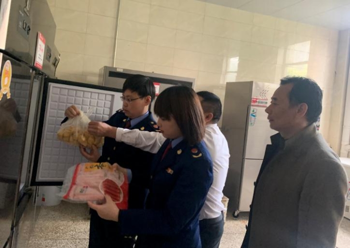 图为该局执法人员检查学校食堂食品原料。
