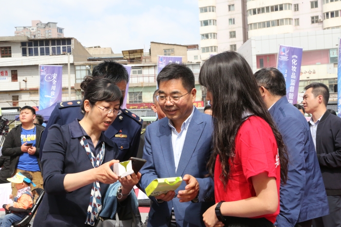 图为启动仪式现场监管人员在化妆品展位上了解产品情况