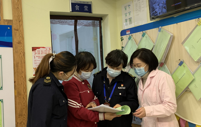 图为执法人员查验食堂饮水机消毒记录。 图为执法人员查验食堂饮水机消毒记录。