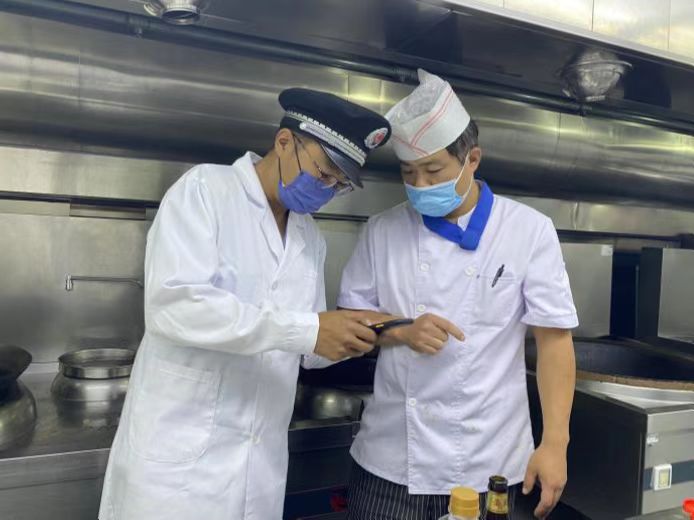图为海淀区市场监管局执法人员检查学校食堂食品安全。