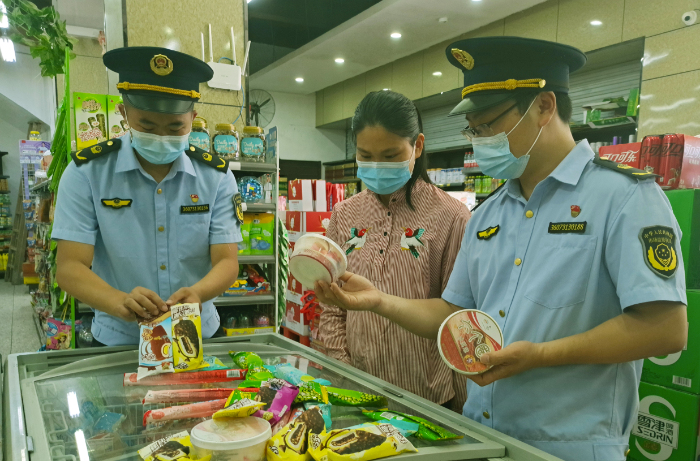 图为7月14日，于都县市场监管局执法人员在一家冷饮店检查冷饮食品标签标识。