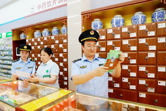 图为5月29日，该局执法人员对一家零售药店的中药饮片进行质量抽检。