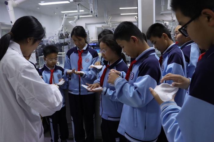 图为小学生们在化妆品实验室体验面膜折叠灌装制作。